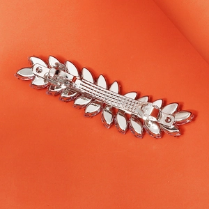 Elegant silver wheat ear hair clip with sparkling crystals on a textured red background