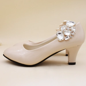 Close-up of sparkling rhinestone crystal decoration on cream-colored high heel shoes