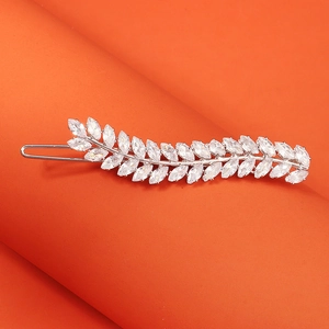 Close-up of silver leaf hair clip with marquise-cut zircon stones on orange background