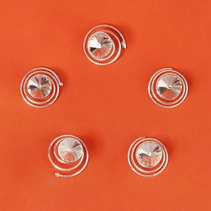 Détail macro de cinq épingles à cheveux spirales argentées avec strass sur fond orange