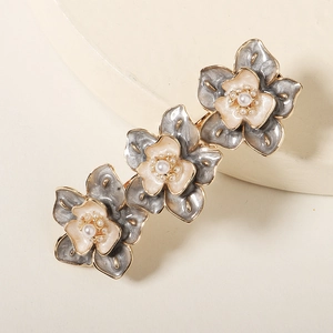 Détail de trois barrettes à fleurs avec émail gris et beige et perles centrales