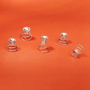 Détail de cinq épingles à cheveux spirales argentées avec strass sur fond orange vif