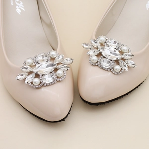 Close-up of luxury rhinestone and pearl shoe clip on a beige bridal flat shoe