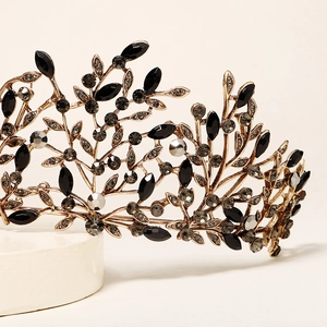Detailopname van gouden vintage kroon met zwarte strassteentjes en verfijnde bladmotieven