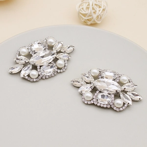 Detailed macro view of sparkling crystal and white pearl shoe clips on a tray