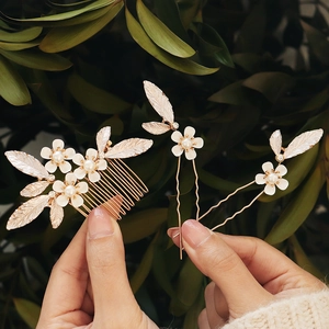 Detail of bridal floral hair comb set with white flowers, pearls, and golden leaves