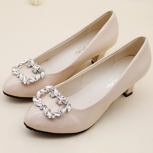 Detail of elegant beige patent leather bridal shoes featuring sparkling rhinestone buckles