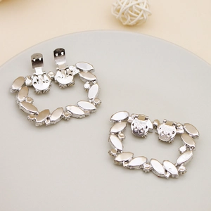 Detail of silver shoe clips with marquise-cut crystals on a minimalist decorative tray