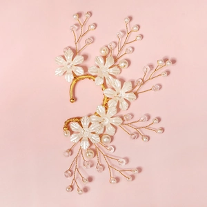 Detail view of handmade bridal ear cuff with white flowers, pearls, and golden wire design