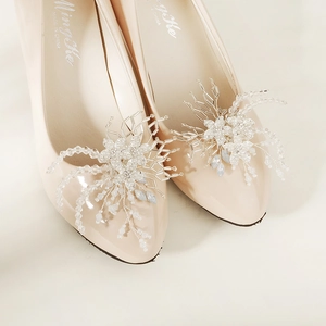 Detailed close-up of luxury bridal shoe clip with pearls and crystal beads on beige pumps