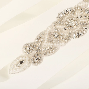 Close-up of handmade bridal belt with ivory ribbon, marquise crystals and pearls