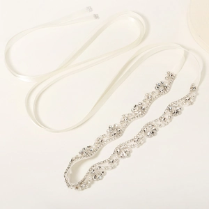 Close-up of crystal rhinestones and white pearls on a bridal sash with silver setting