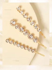 Detailed view of three gold rhinestone hair clips including wave and straight designs