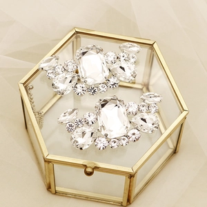 Close-up of sparkling rhinestone shoe clips on a glass box with romantic tulle background
