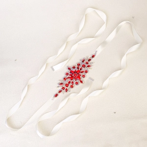 Detailed macro view of handcrafted red crystal and rhinestone bridal sash on white satin