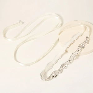 Detail of bridal belt showing ivory satin ribbon with intricate rhinestone and pearl wave patterns