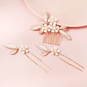 Detail of bridal hair comb set with white enamel flowers and pearls on gold leaves
