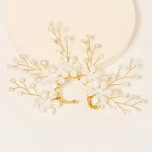 Macro view of gold wire bridal ear cuff with matte flowers and white pearls