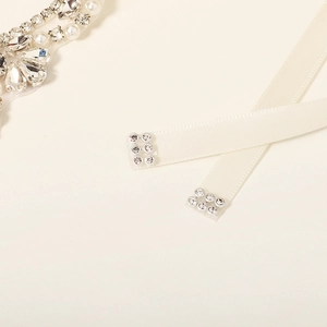 Detail view of bridal sash featuring pear-shaped rhinestones and pearls on satin ribbon