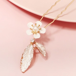 Close-up of a gold U-shaped bridal hair pin with white flowers and feather pendants