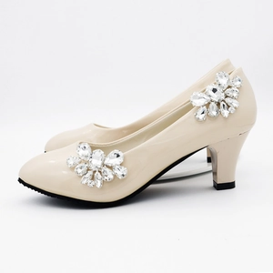 Close-up of sparkling rhinestone flower buckles on beige patent leather wedding shoes