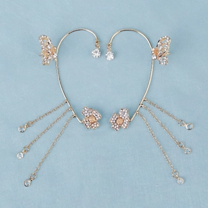 Detail of luxury butterfly ear cuffs with gold finish, sparkling crystals and long tassels