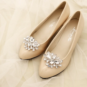 Detailed close-up of apricot pointed-toe shoes with sparkling crystal floral buckles