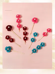 Close-up of floral hair clips with fabric roses, pearls, and gold alloy metal details