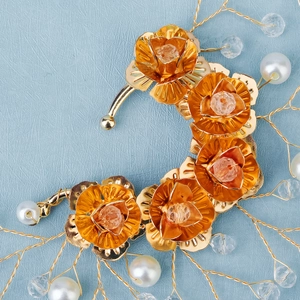 Detail of handmade bridal ear cuff with gold metal flowers, crystals and white pearls