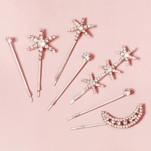 Détail de 7 barrettes argentées avec strass célestes sur un fond rose doux