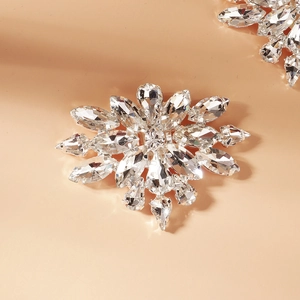 Macro detail of snowflake shoe clip with marquise rhinestones on a warm beige background