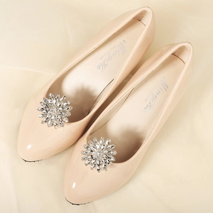 Close-up of sparkling rhinestone flower buckle on elegant beige pointed flat shoes