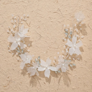 Handmade bridal flower headband with white fabric blossoms and blue crystals on beige paper