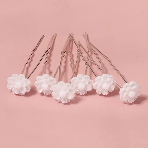 Set of six white floral hair pins for weddings and parties on a soft pink background
