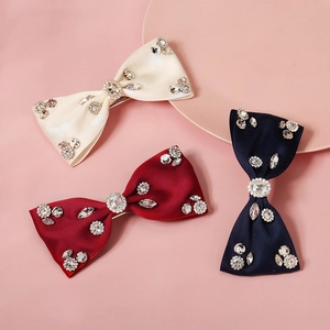 Detailed view of handmade bow hair clips in beige, wine red, and navy with sparkling rhinestones