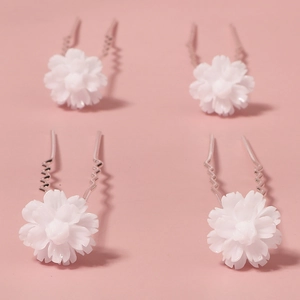 Macro detail of four white floral hair pins with silver wavy U-shaped metal forks