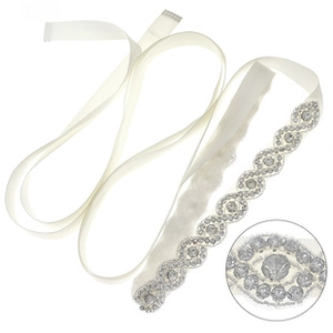 Macro detail of luxury crystal bridal belt with silver rhinestones on ivory satin ribbon