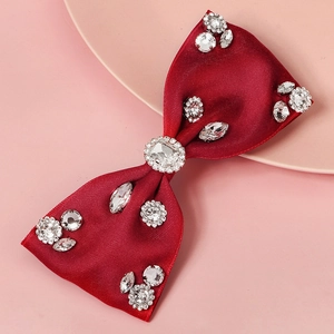Close-up of red satin bow hair clip with sparkling rhinestones on a decorative plate