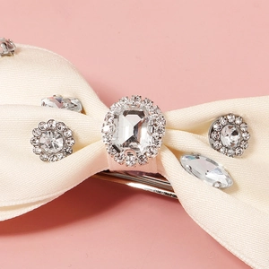 Close-up of cream bow hair clip with sparkling rhinestones and metal spring closure
