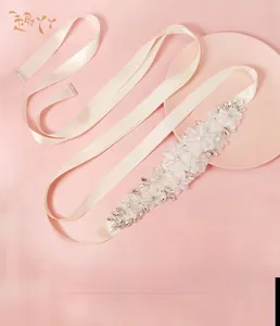 Dettagli di una cintura da sposa in avorio con fiori di pizzo e strass