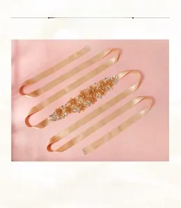 Dettaglio di cintura da sposa con fiore di perline fatte a mano oro champagne e paillettes