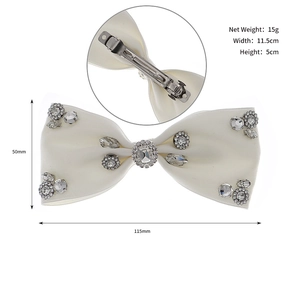 Detailed view of white satin bow hair clip with sparkling rhinestones and metal spring clip