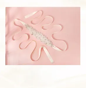 Dettaglio della cintura da sposa fatta a mano con fiori di pizzo bianco e perle