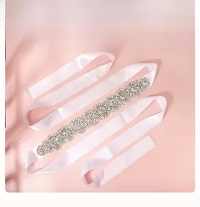 Détail d'une ceinture de mariée avec strass argentés et perles sur ruban de satin rose