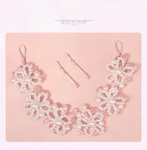 Macro detail of bridal hairband with white pearls and crystal flowers on pink background