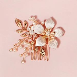 Handmade bridal hair comb with white pearls, crystals and gold leaves on pink background