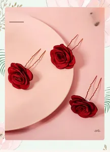 Lot de trois épingles à cheveux roses en tissu rouge foncé sur un plateau rose