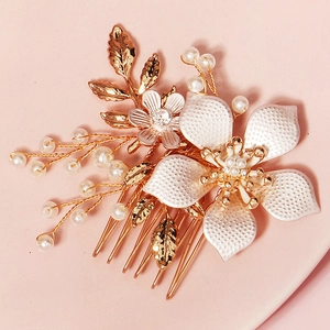 Elegant bridal hair comb featuring white crystal flowers and pearls on a gold metal base