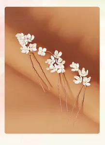 Detailansicht von drei weißen floralen Braut-Haarnadeln mit goldenen U-förmigen Stielen