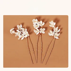Detailset aus drei weißen Blumen-Haarnadeln mit goldenem Metalldraht für Brautfrisuren